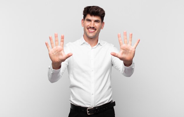 Junger Mann lächelt und sieht freundlich aus, zeigt Nummer zehn oder Zehntel mit der Hand nach vorne, Countdown