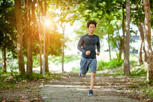 Junger Mann läuft in der Natur Gesunder LebensstilAktiver gesunder Läufer beim Joggen im FreienJunger Mann, der in einem bewaldeten Waldgebiet läuft