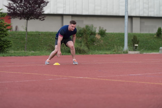 Junger Mann läuft zum Kegel auf dem Sportplatz