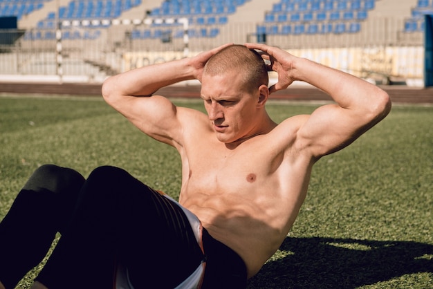 Foto junger mann macht crunches beim training der bauch- und brustmuskulatur im stadion