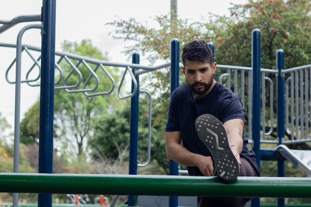 Junger Mann macht Dehnübungen während seines Trainings in einem Park in der Stadt