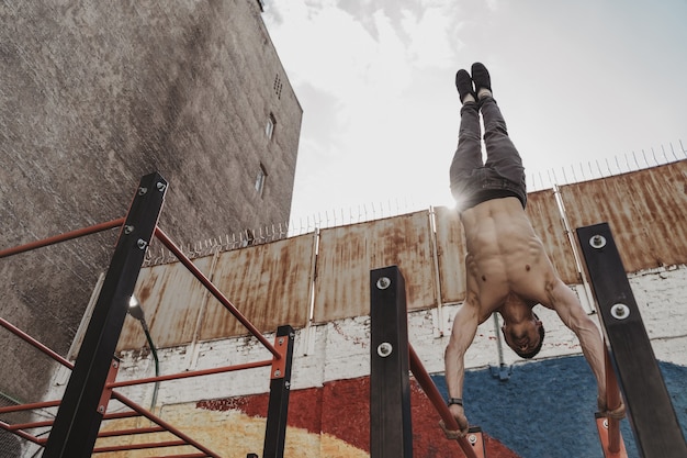 Junger Mann macht Handstand Liegestütze Übung auf Barren