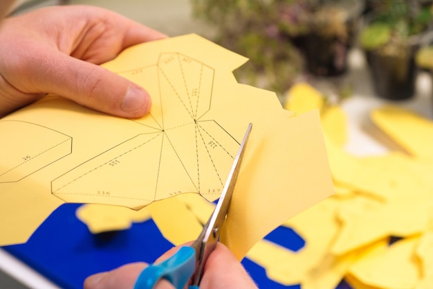 Junger Mann macht Papierfiguren Jungenhände schneiden gelbes Origami mit einer Schere Machen Sie 3D-Papierfigur Hobby-Konzept