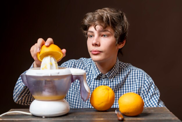 Junger Mann macht Saft mit frischem Orangenb