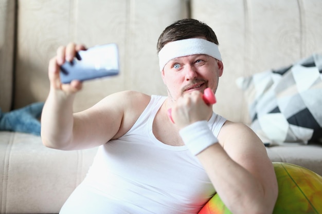 Junger Mann macht Selfie mit Hanteln in den Händen