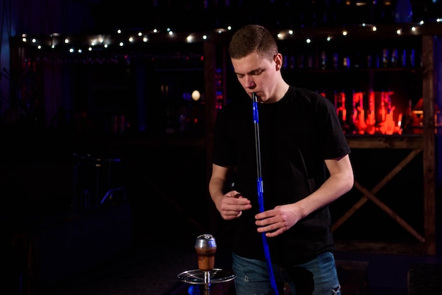 Junger Mann macht Shisha mit Kokosnusskohle zum Entspannen und Shisha-Rauch