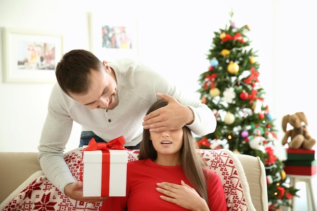 Junger Mann macht Weihnachtsüberraschung für seine Freundin zu Hause