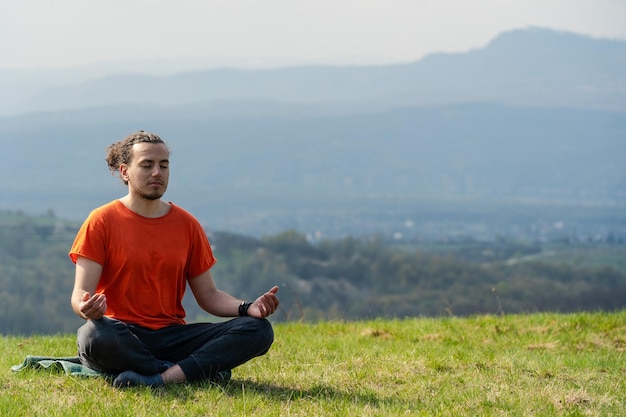 Junger Mann macht Yoga auf der Felsspitze Meditation