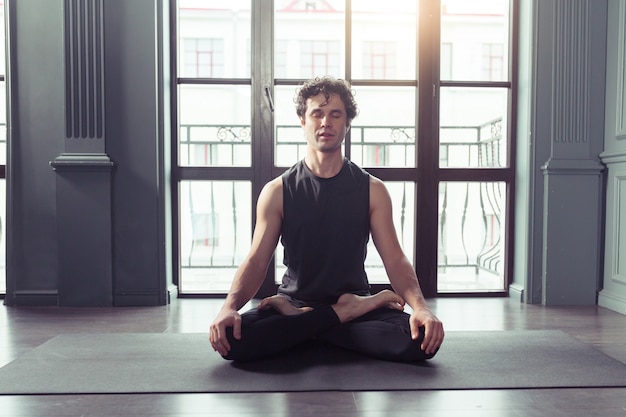 Junger Mann meditiert beim Üben von Yoga im Lotussitz. Freiheit Ruhe und Entspannungskonzept