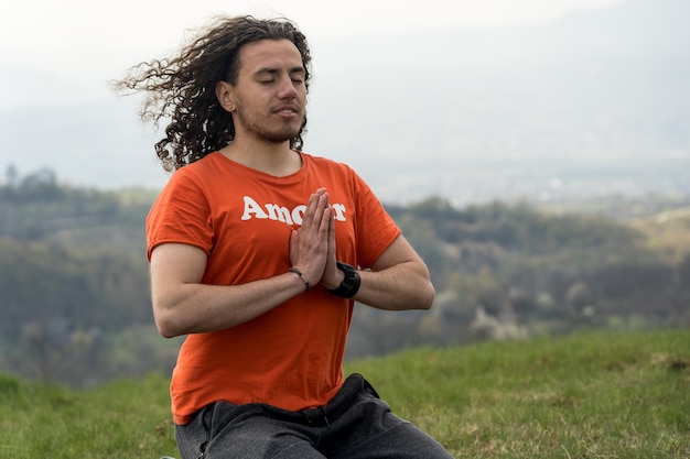 Junger Mann meditiert Yoga auf dem Berg Entspannen Sie sich und beruhigen Sie sich