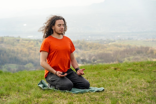 Junger Mann meditiert Yoga auf dem Berg Entspannen Sie sich und beruhigen Sie sich