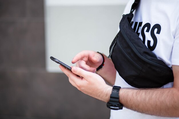 Junger Mann mit Bart, der auf einem Handy läuft und spricht Gutes Gespräch Glücklicher junger bärtiger Mann, der auf dem Handy spricht und wegschaut, während er in der Nähe der grauen Wand steht Video-Chat-Telefon