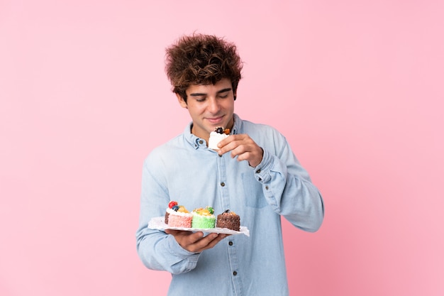 Junger Mann mit blauem Hemd kleine Kuchen essend