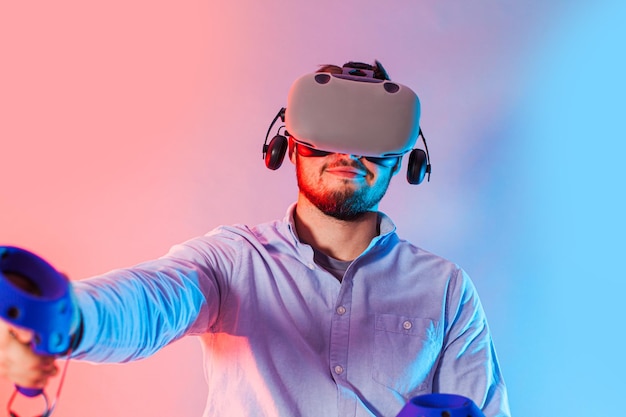 Junger Mann mit der Virtual-Reality-Brille zwei Gamepad und Videospiel spielen