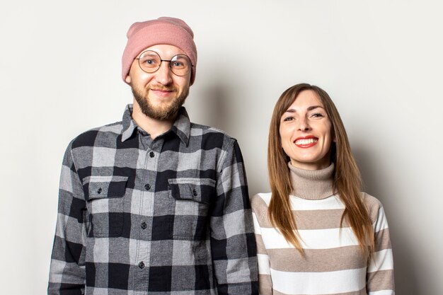 Junger Mann mit einem Bart in einem Hut und einem karierten Hemd und einem Mädchen in einem Pullover