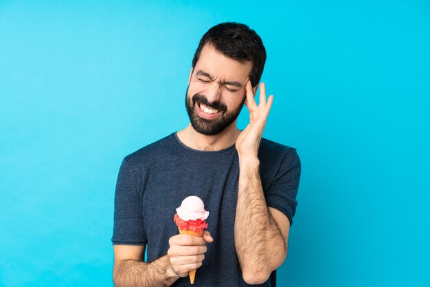 Junger Mann mit einem Kornetteis über Blau mit Kopfschmerzen