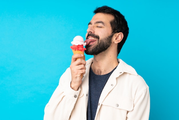 Junger Mann mit einem Kornetteis über isolierter blauer Wand