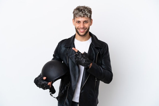 Junger Mann mit einem Motorradhelm isoliert auf weißem Hintergrund, der auf die Seite zeigt, um ein Produkt zu präsentieren