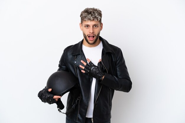 Junger Mann mit einem Motorradhelm isoliert auf weißem Hintergrund überrascht und schockiert, während er nach rechts schaut