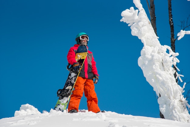 Junger Mann mit einem Snowboard auf den Bergen