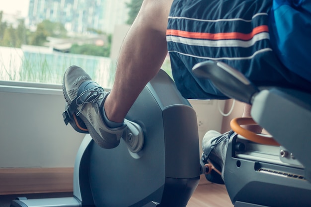 Junger Mann mit einem Spinning-Bike in einem Indoor-Fitnesscenter