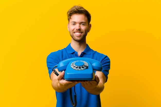 Junger Mann mit einem Telefon gegen Orange