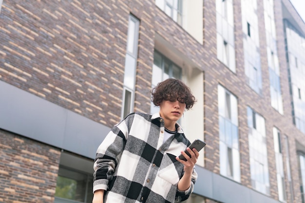 Foto junger mann mit einem telefon vor dem hintergrund von stadtgebäuden