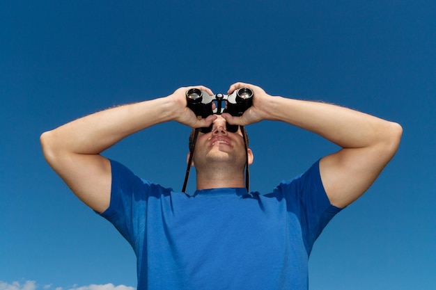 Foto junger mann mit fernglas blauer himmel als hintergrund