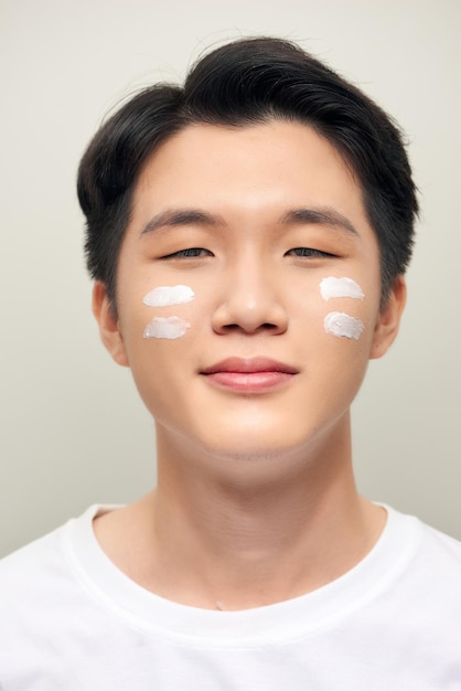 Junger Mann mit Feuchtigkeitscreme im Gesicht