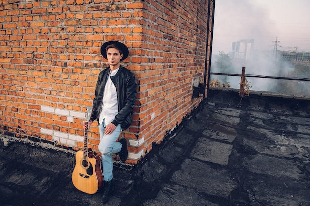 Junger Mann mit Gitarre auf dem Hintergrund einer Mauer