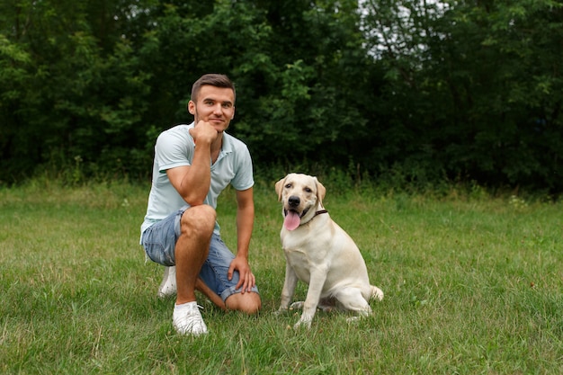 Junger Mann mit glücklichem Labrador im Park