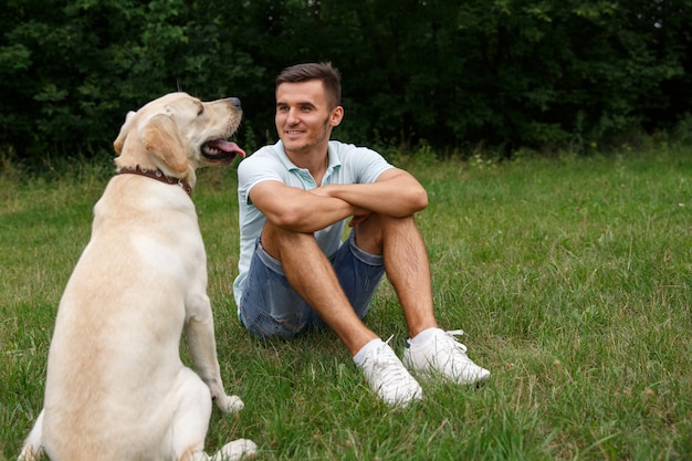 Junger Mann mit glücklichem Labrador im Park