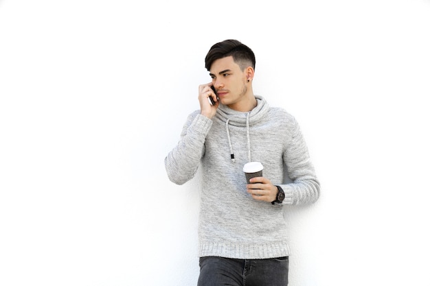 Junger Mann mit grauem Pullover über weißer Wand