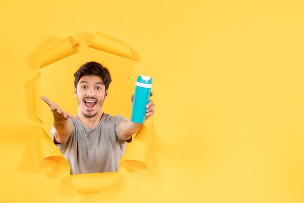 junger Mann mit grüner Flasche auf gelbem Hintergrund Sport Workout Gymnastik Übung fit