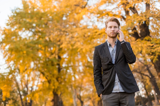 Junger Mann mit Handy im Herbstpark