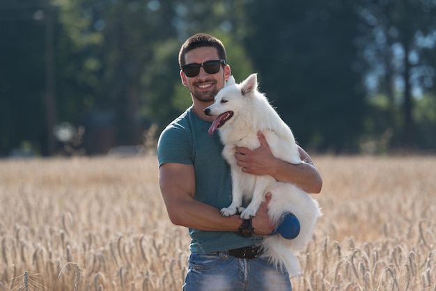Junger Mann mit Hund Deutscher Spitz im abgeernteten Feld