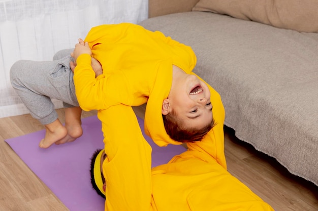 Junger Mann mit kleinem Jungen, der zu Hause Fitnessübungen macht. Vater und Sohn haben Spaß beim Sport. Papa und sein Kind beim Training. Sport, Yoga. Training in der Wohnung. Gesunder Lebensstil, Familie.