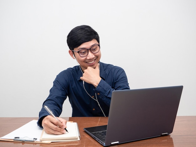 Junger Mann mit Kopfhörer, der mit Laptop am Tisch arbeitetMann, der am Arbeitsplatz arbeitet