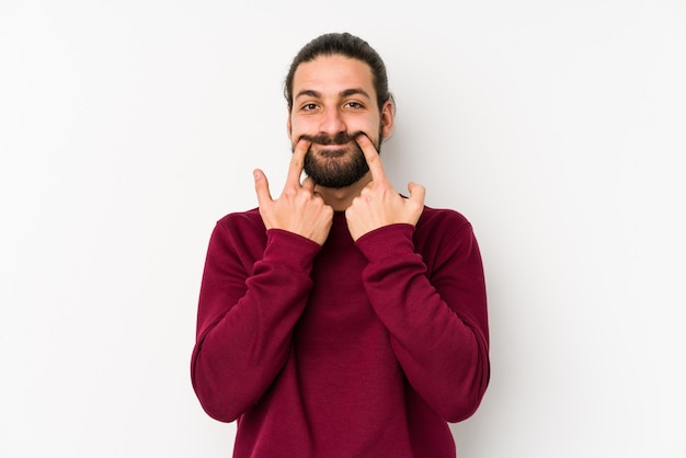 Junger Mann mit langen Haaren, isoliert auf einer weißen Wand, die zwischen zwei Optionen zweifelt.