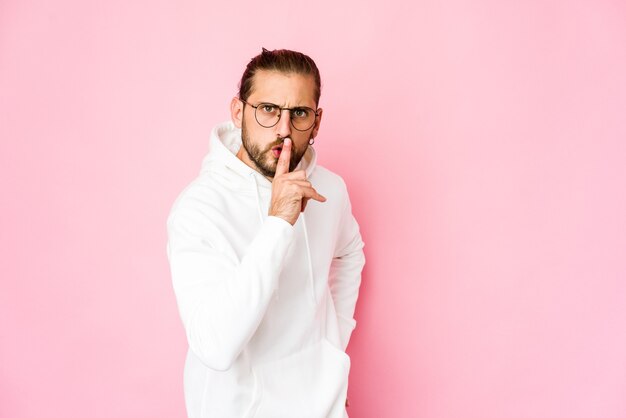 Junger Mann mit langen Haaren sieht geheim aus oder bittet um Stille.