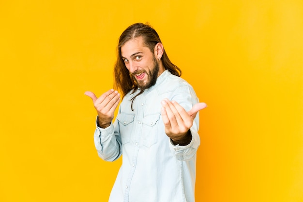 Junger Mann mit langen Haaren zeigt mit dem Finger auf dich, als ob die Einladung näher kommt.