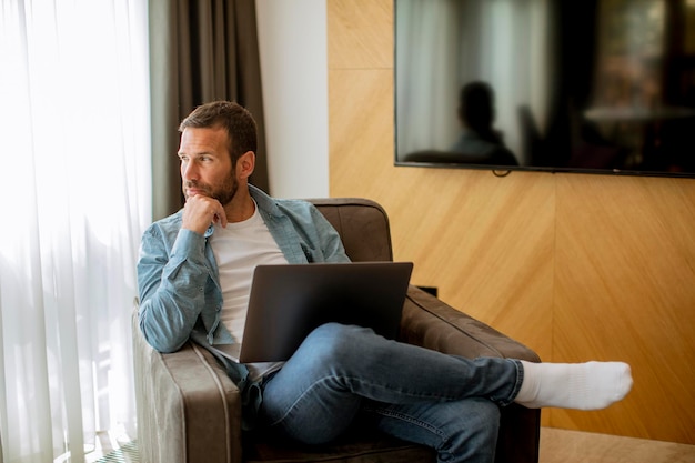 Junger Mann mit Laptop im Wohnzimmer