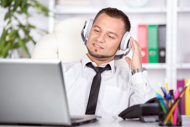 Junger Mann mit Laptop, Telefon am Tisch.