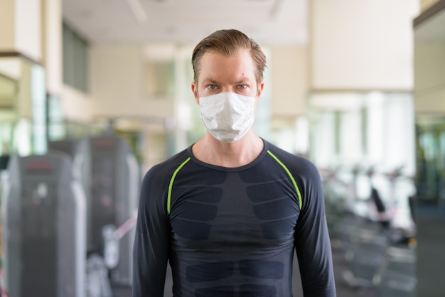 Junger Mann mit Maske zum Schutz vor Coronavirus-Ausbruch im Fitnessstudio während Coronavirus covid-19