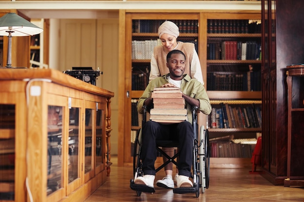 Junger Mann mit Rollstuhl in der Bibliothek