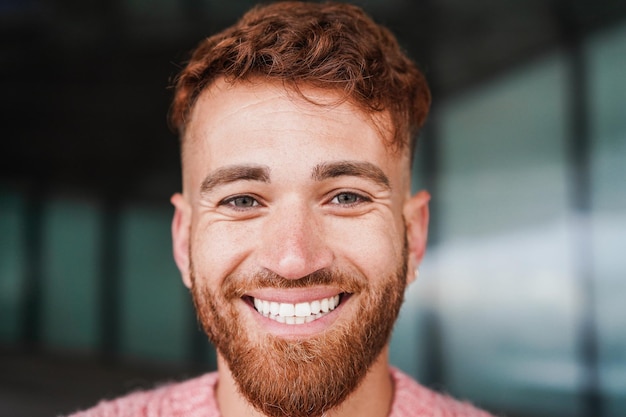 Foto junger mann mit roten haaren lächelt draußen in die kamera