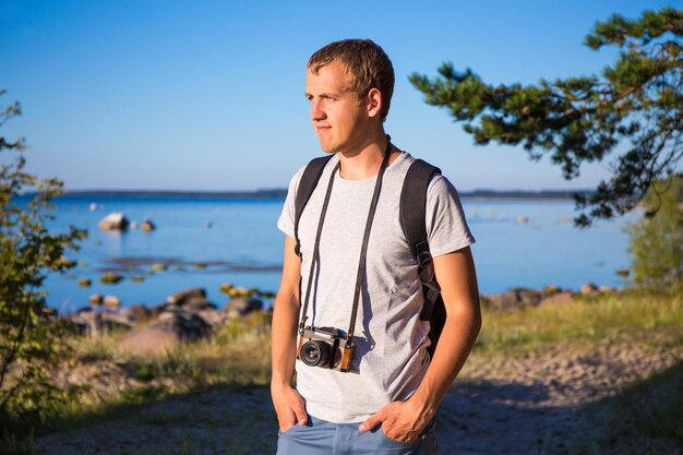 Junger Mann mit Rucksack und Retro-Kamera am Strand