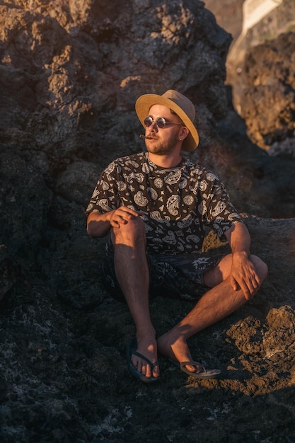 Junger Mann mit Sonnenbrille, der einen Joint raucht