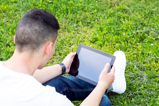 Junger Mann mit Tablette in einem Park