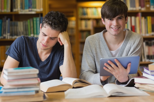 Junger Mann mit Tabletten-PC in der Bibliothek